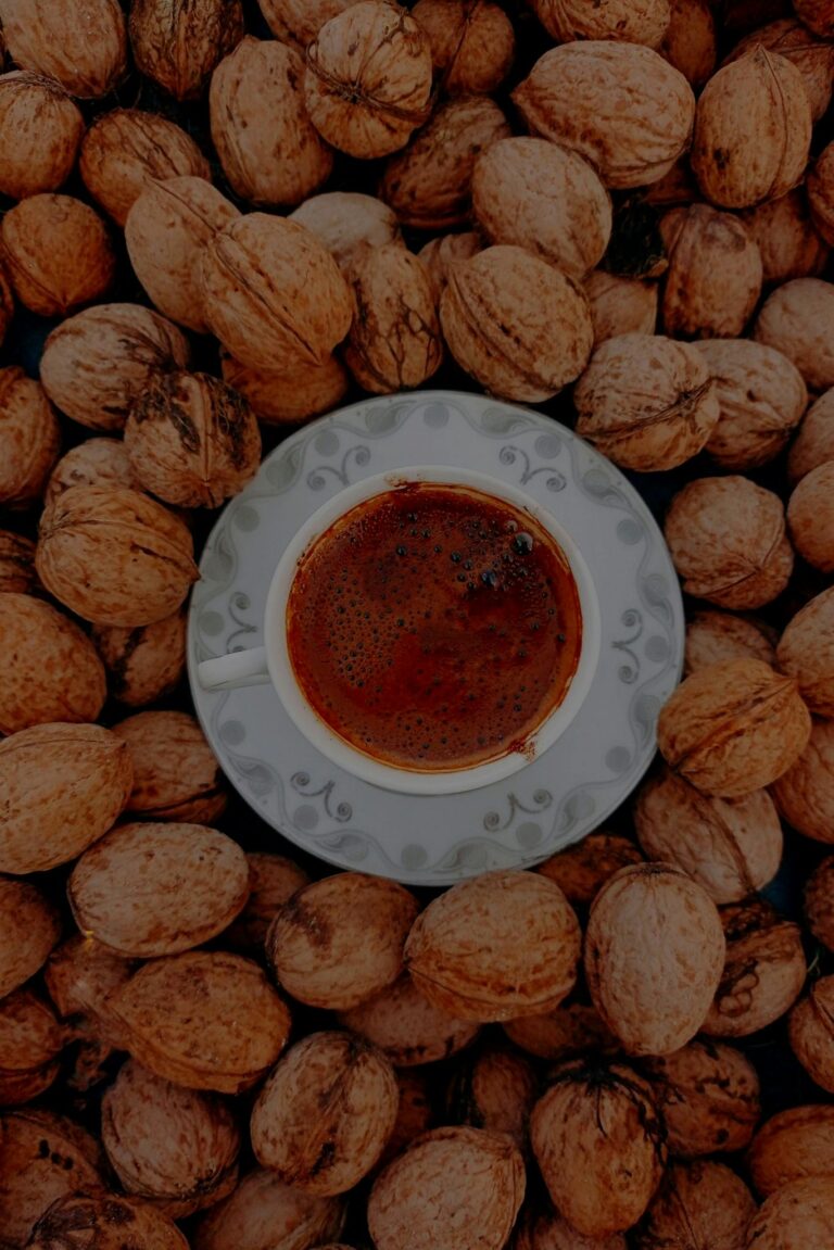 A warm coffee cup placed amidst a bed of walnuts for an inviting breakfast vibe.