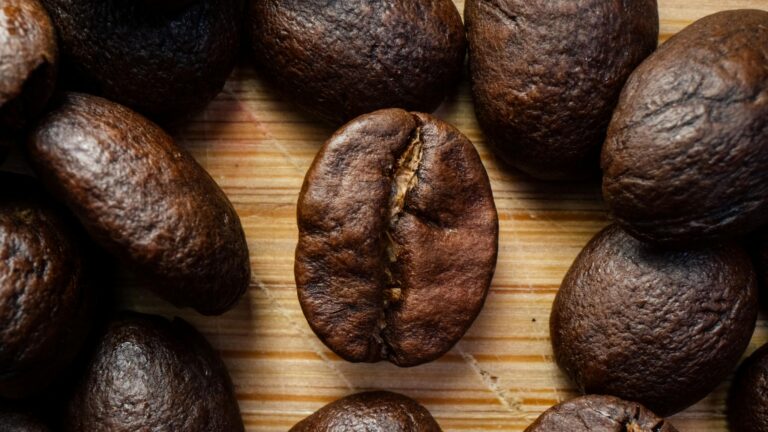 Macro shot showcasing roasted coffee beans on wooden surface for a rich, aromatic appeal.